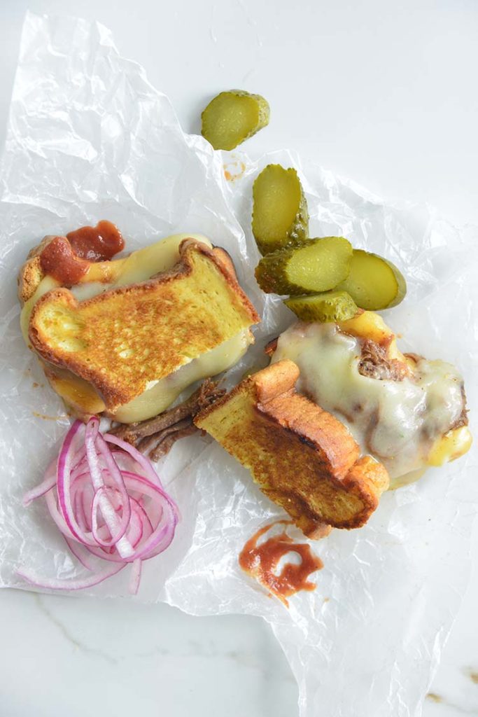 3 cheese keto grilled cheese sandwich on parchment paper with pickles and red onions