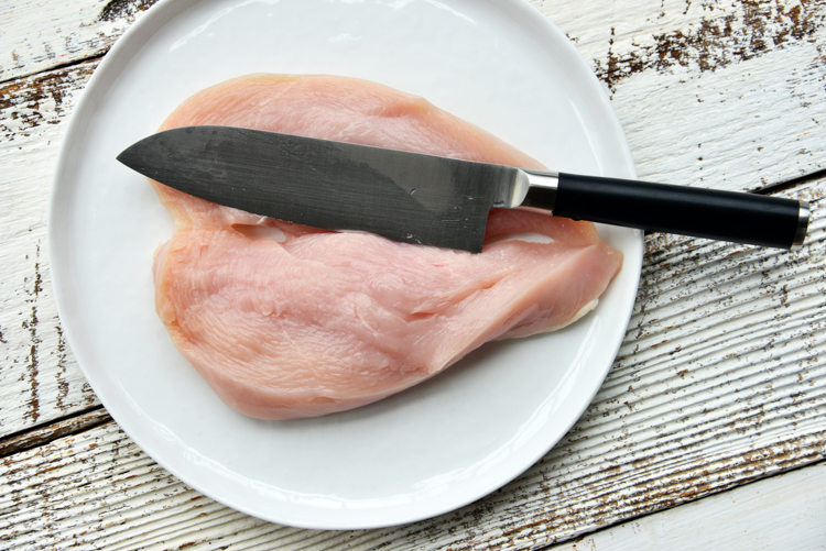 chicken breast on a white plate with a knife