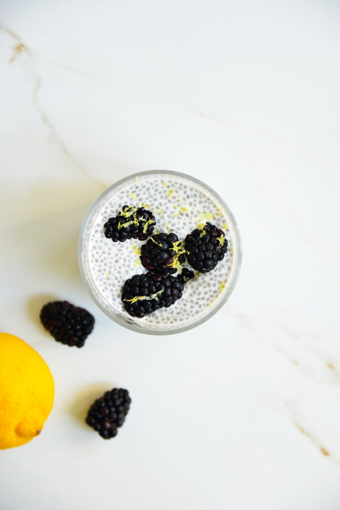 blackberry lemon chia pudding in a glass with a spoon and blackberries on top