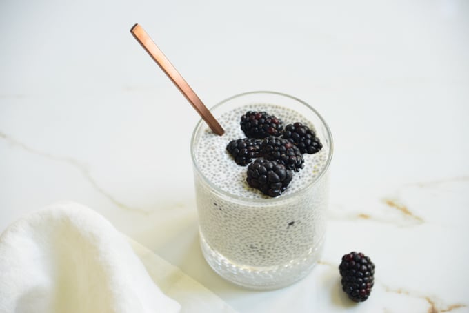 blackberry lemon chia pudding in a glass with a spoon and blackberries on top