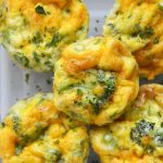 close up vertical image of broccoli and cheddar egg muffins in a glass storage container