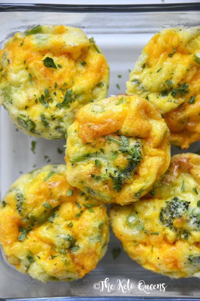close up vertical image of keto breakfast meal prep of broccoli and cheddar egg muffins in a glass storage container