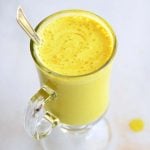 image of golden milk latte in a clear glass on a white background