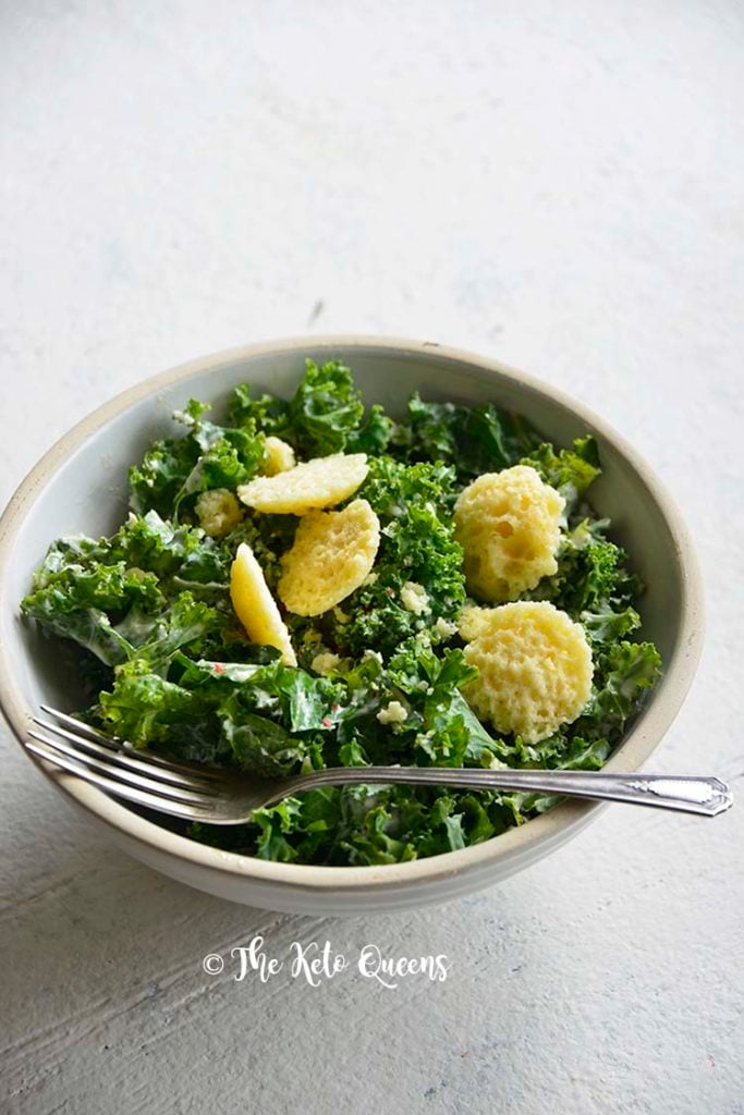 vertical image of a caesar salad in a white bowl on a white surface