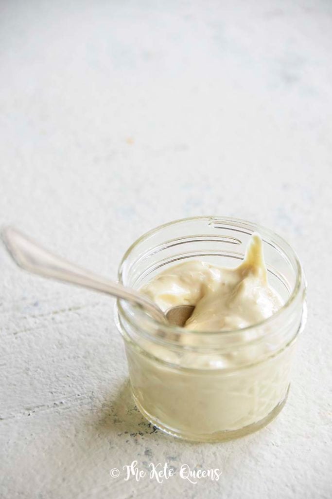 Vertical image of creamy caesar salad dressing in a small glass mason jar