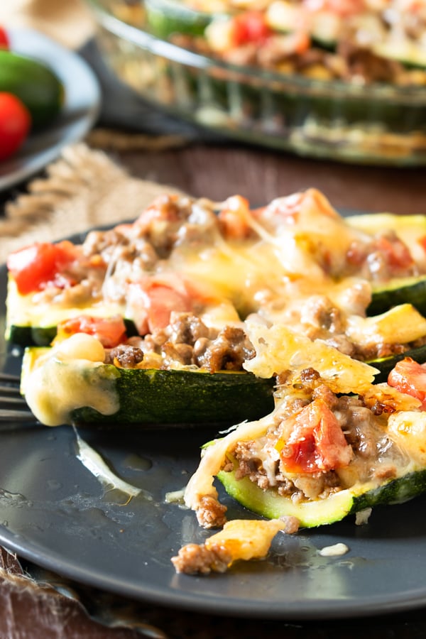close up of slow cooker BBQ brisket stuffed zucchini boats on dark plates