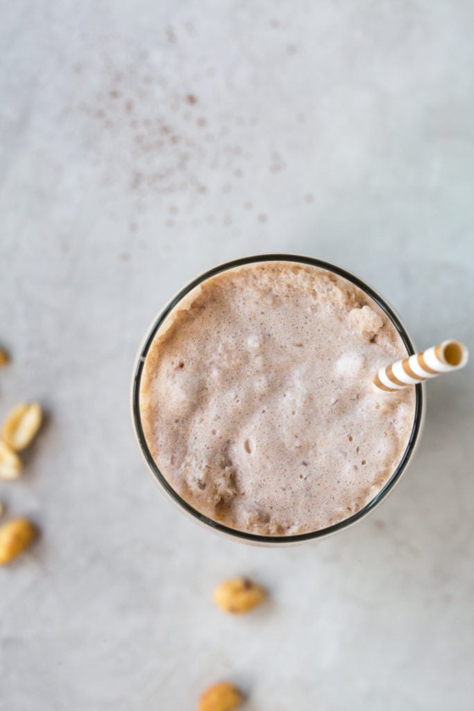 low carb chocolate peanut butter milkshake in a tall glass with a straw on a grey background