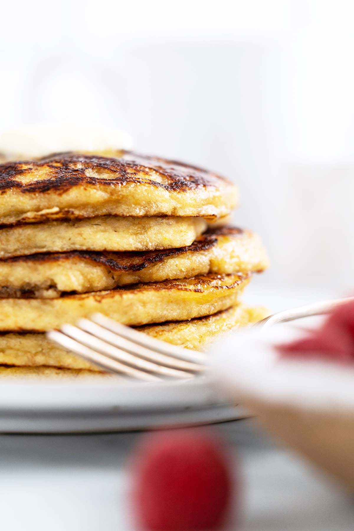 close up stack of pancakes with red raspberries