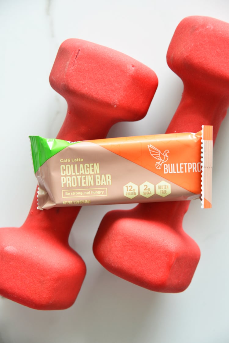 collagen protein bar on top of red dumbbells
