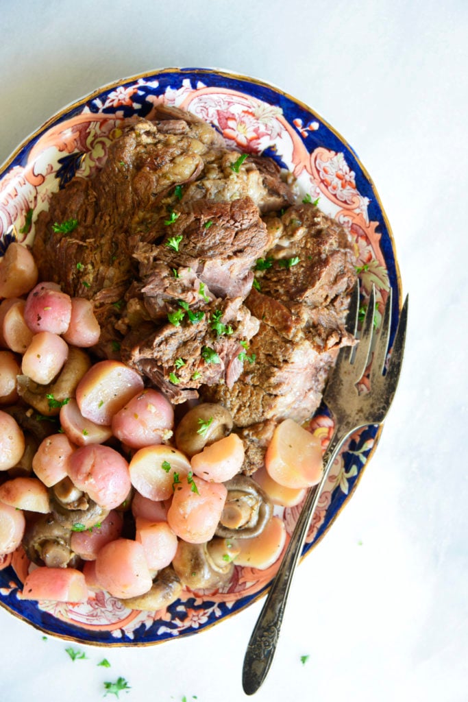 close up image instant pot pot roast with radishes on a white background