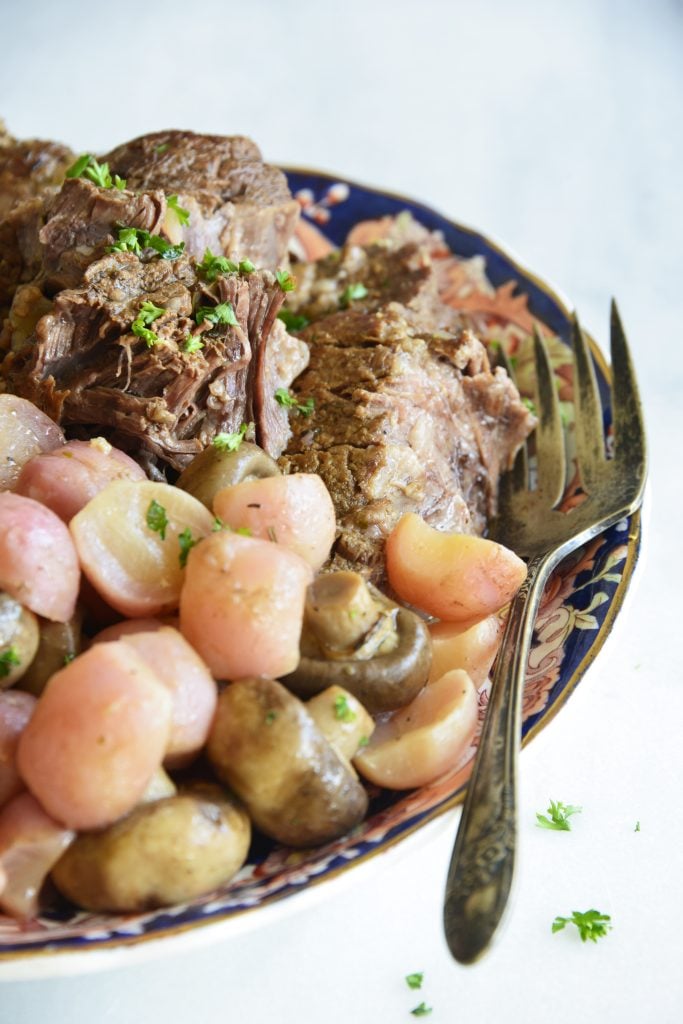 instant pot pot roast with radishes on a white background
