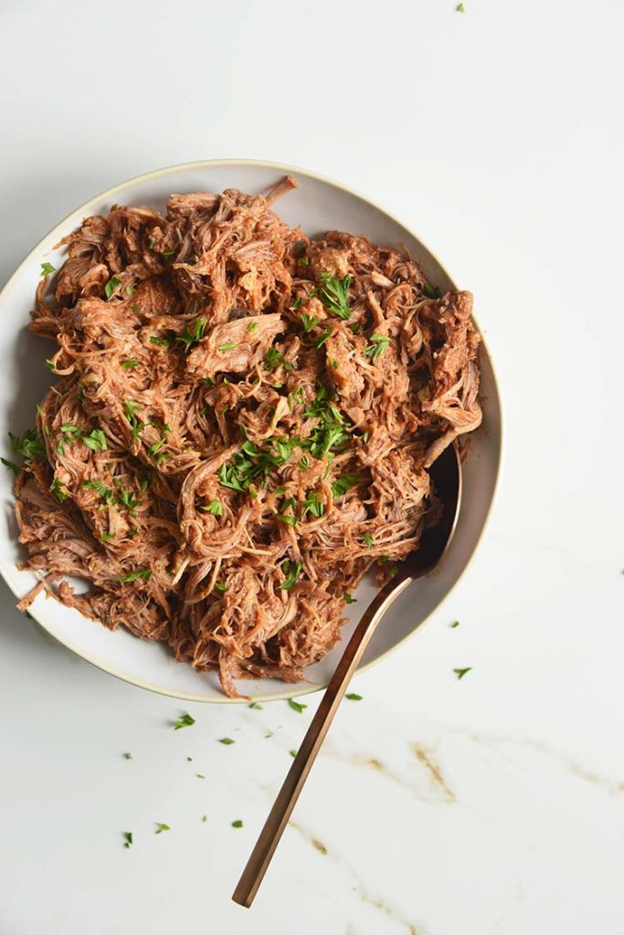 keto bbq pulled pork on a white bowl with parsley