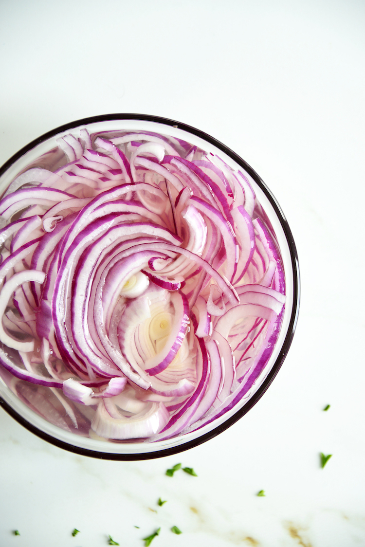 raw red onions in a white bowl
