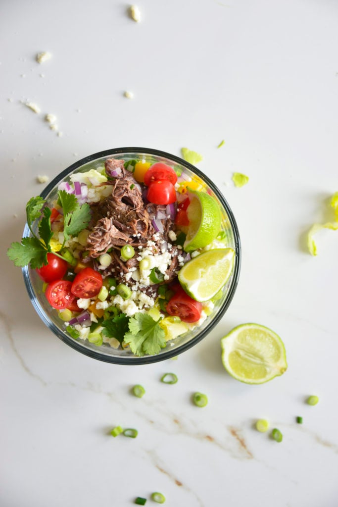 Shredded Beef Keto Taco Salad Recipe in a glass bowl on a white background with lime