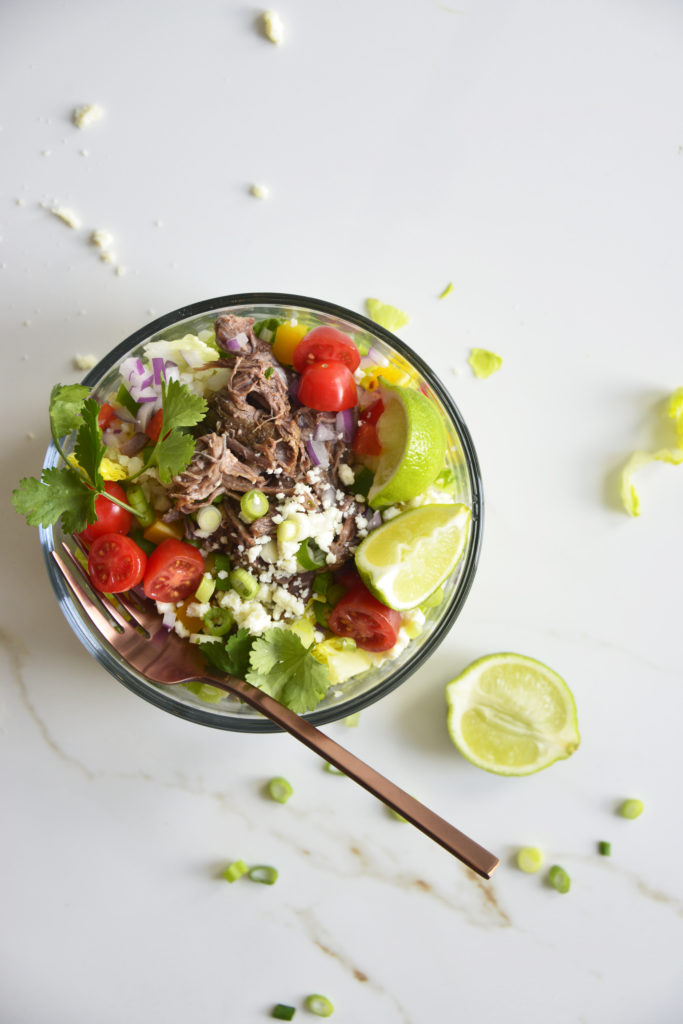 Shredded Beef Keto Taco Salad Recipe in a glass bowl on a white background with lime