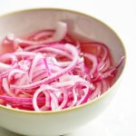 close up of pickled red onions in a white bowl