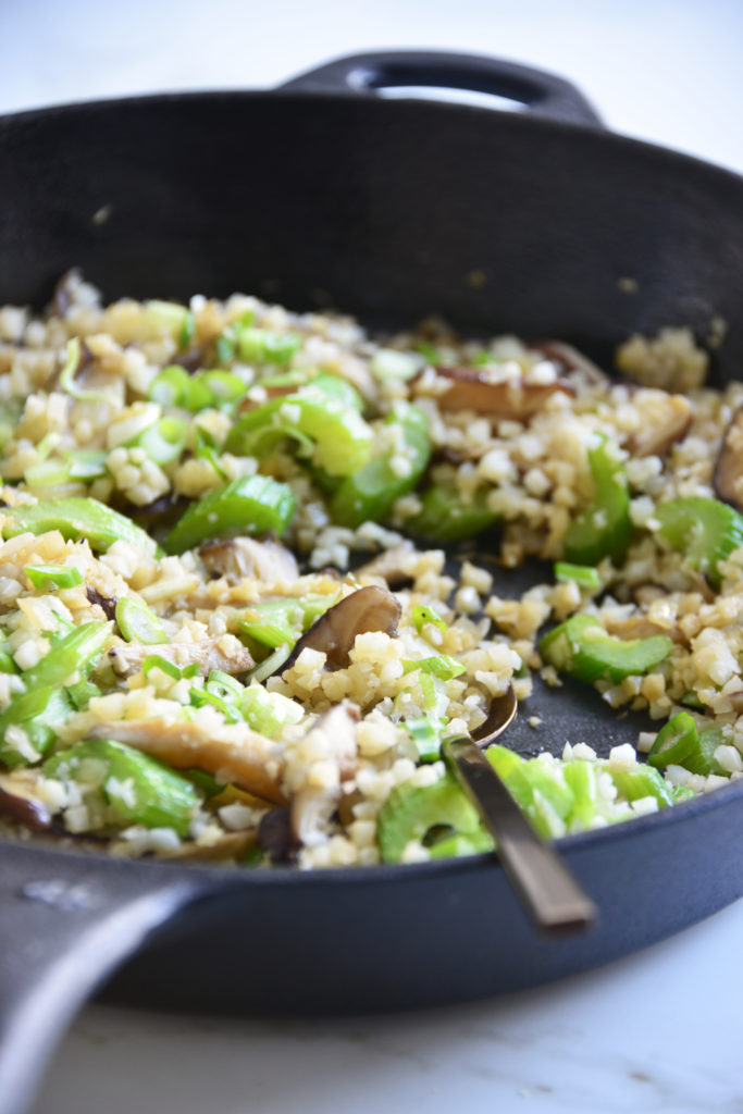 cauliflower fried rice in a cast iron skillet with a spoon