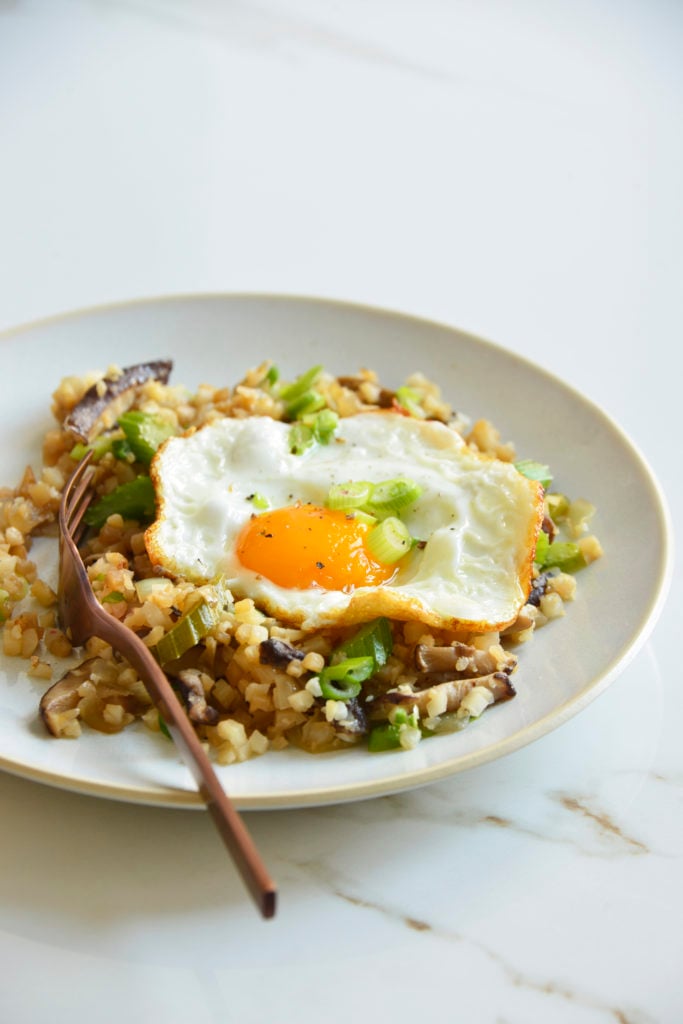 cauliflower fried rice on plate topped with an egg