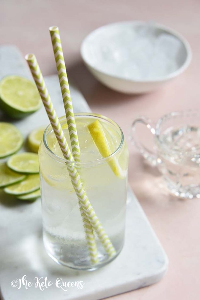 keto lemonade in a clear glass on a white slate with slices of lemon