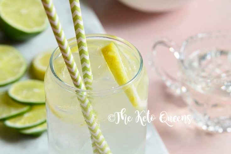 keto lemonade in a clear glass on a white slate with slices of lemon