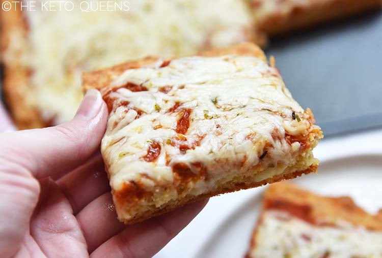 hand holding slice of keto pizza