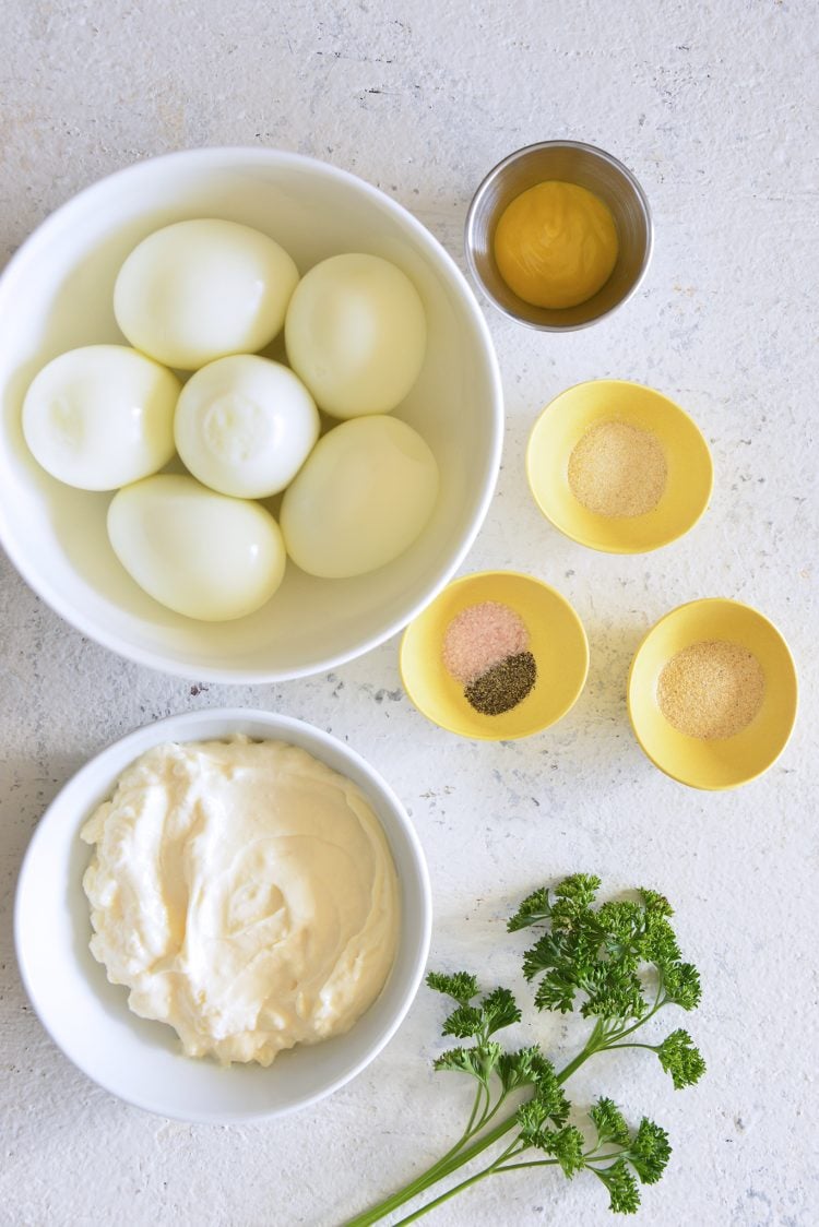 Image of ingredients such as eggs, mayo, yellow mustard, garlic powder, onion powder, salt, black pepper, and fresh parsley