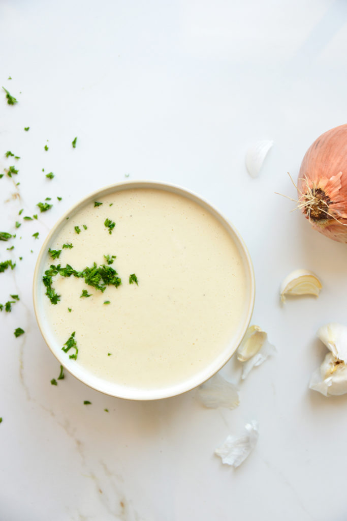 keto cauliflower soup on a white background with parsley and onion