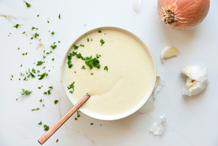 keto cauliflower soup on a white background with parsley and onion