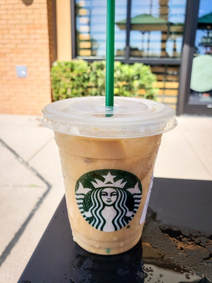 Tired of boring black coffee? Check out my top 5 Keto Starbucks Drinks to brighten your morning. picture of a starbucks iced coffee with heavy whipping cream out side on a table