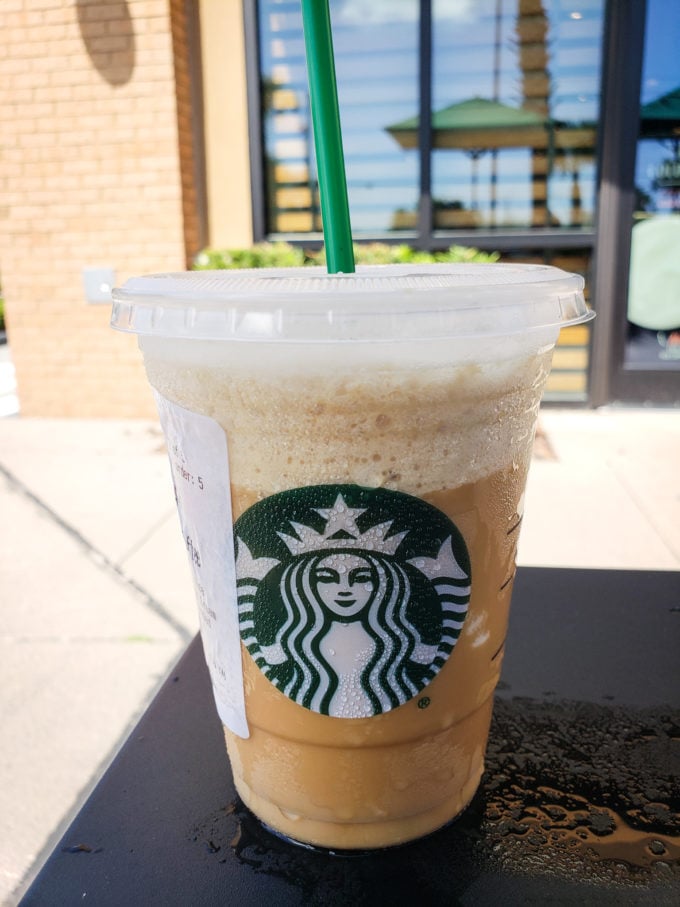 Tired of boring black coffee? Check out my top 5 Keto Starbucks Drinks to brighten your morning. Image of a Keto Frappuccino outside of a starbucks on a table