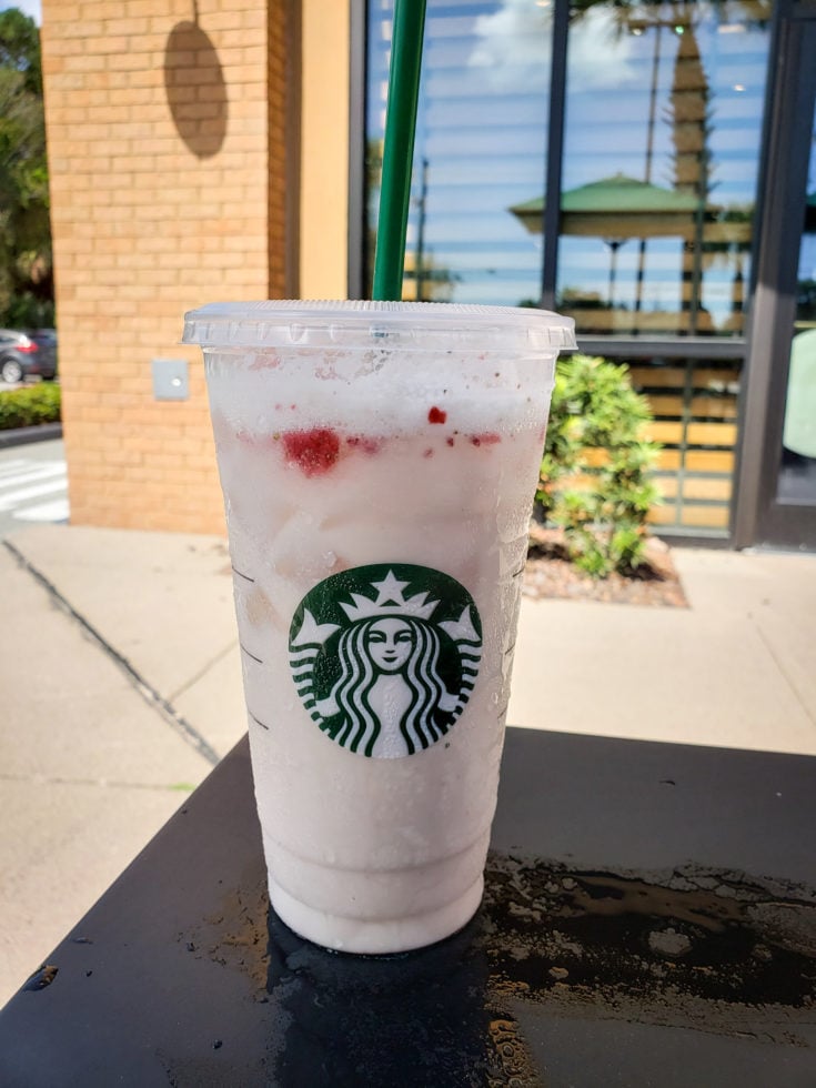 Tired of boring black coffee? Check out my top 5 Keto Starbucks Drinks to brighten your morning. a picture of a keto pink drink on a table outside in the sun