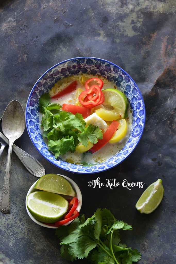 Vertical image of a bowl of thai coconut curry with red bell peppers and yellow squash.