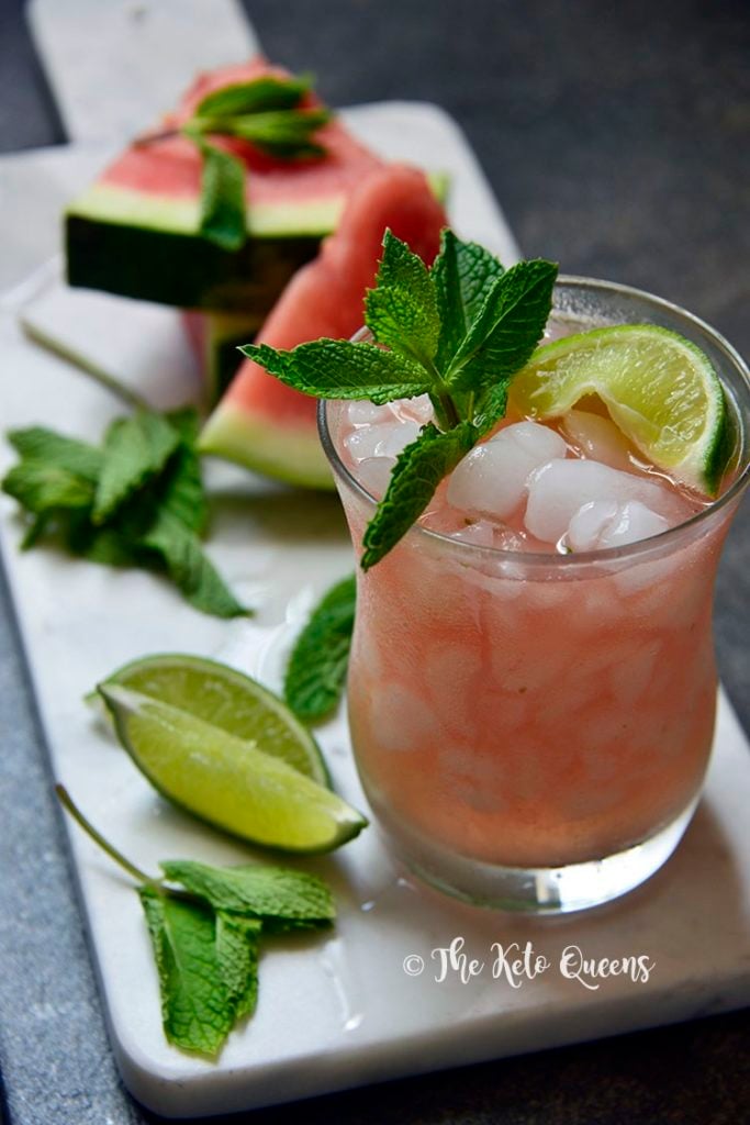 low carb watermelon mojito in a glass with lime and mint on a white tray