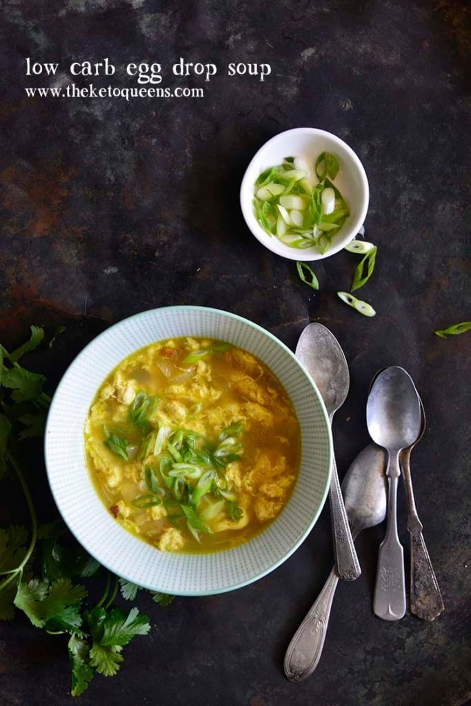 Pinnable image of egg drop soup over head shot with scallions and spoons on a dark surface