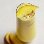 low carb peach bellini in a stemless glass with peach slices on top