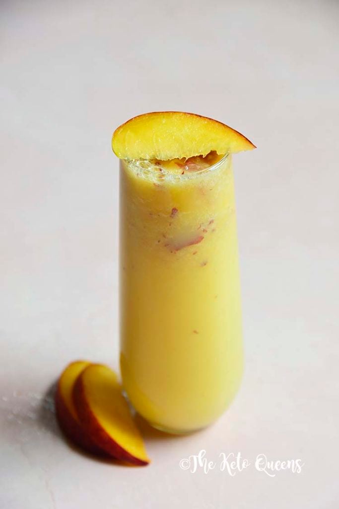 low carb peach bellini mocktail in a seamless glass with peaches on top