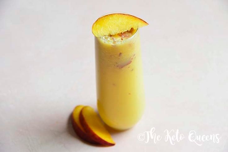 low carb peach bellini mocktail in a seamless glass with peaches on top