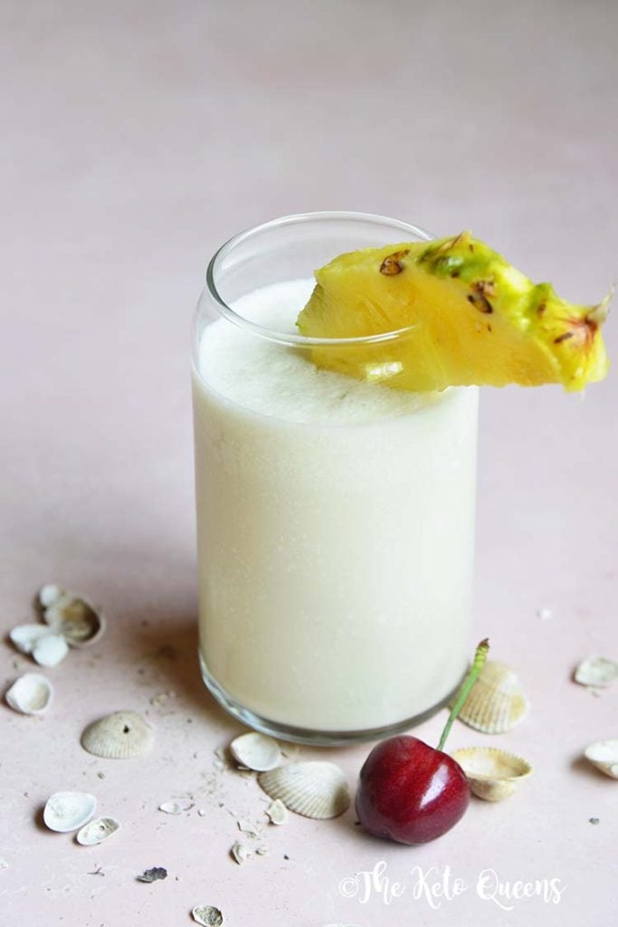keto pina colada in a glass cup with pineapple and cherry