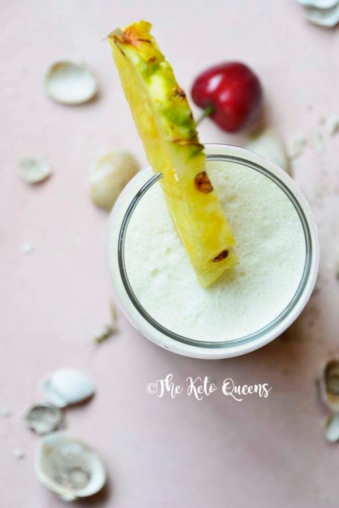 keto pina colada in a glass cup with pineapple and cherry