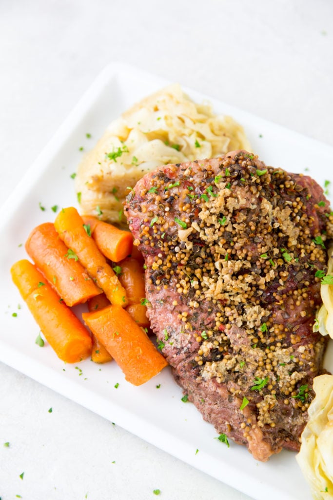 vertical image of corned beef, cabbage and carrots on a white plate