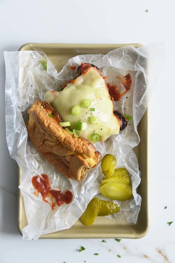 Keto BBQ Pulled Pork Sandwich on parchment paper with scallions and pickles