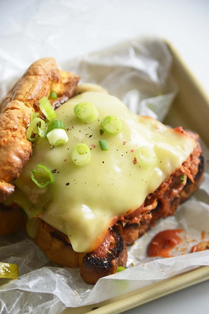 Keto BBQ Pulled Pork Sandwich on parchment paper with scallions and pickles