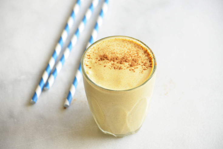 keto pumpkin smoothie in a clear glass with blue striped straws
