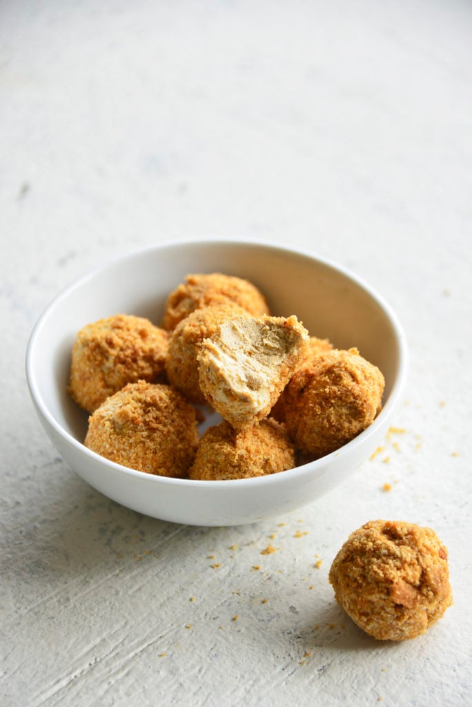 Keto Pumpkin Spice Cream Cheese Fat Bombs in a white bowl with a bite taken out