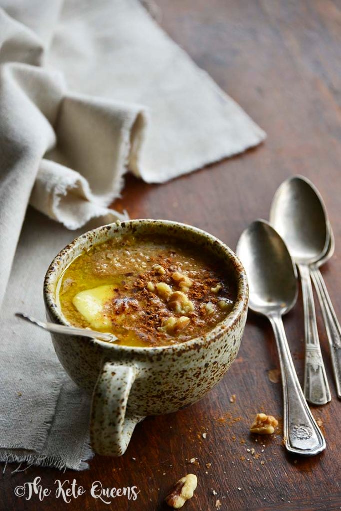 pumpkin spice keto oatmeal in a mug with spoons and linen on a wood surface