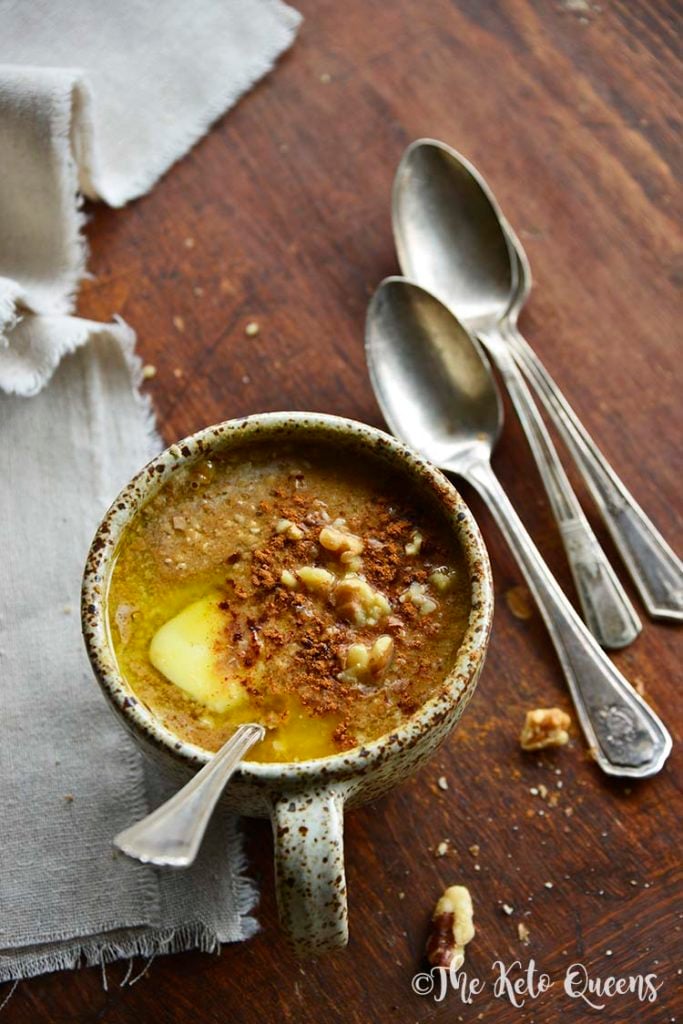 pumpkin spice keto oatmeal in a mug with spoons and linen on a wood surface