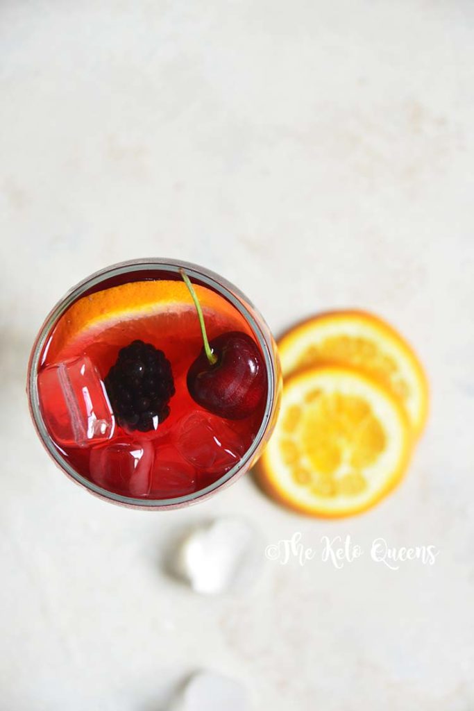 keto sangria mocktail recipe in a clear glass garnished with cherries and orange slices