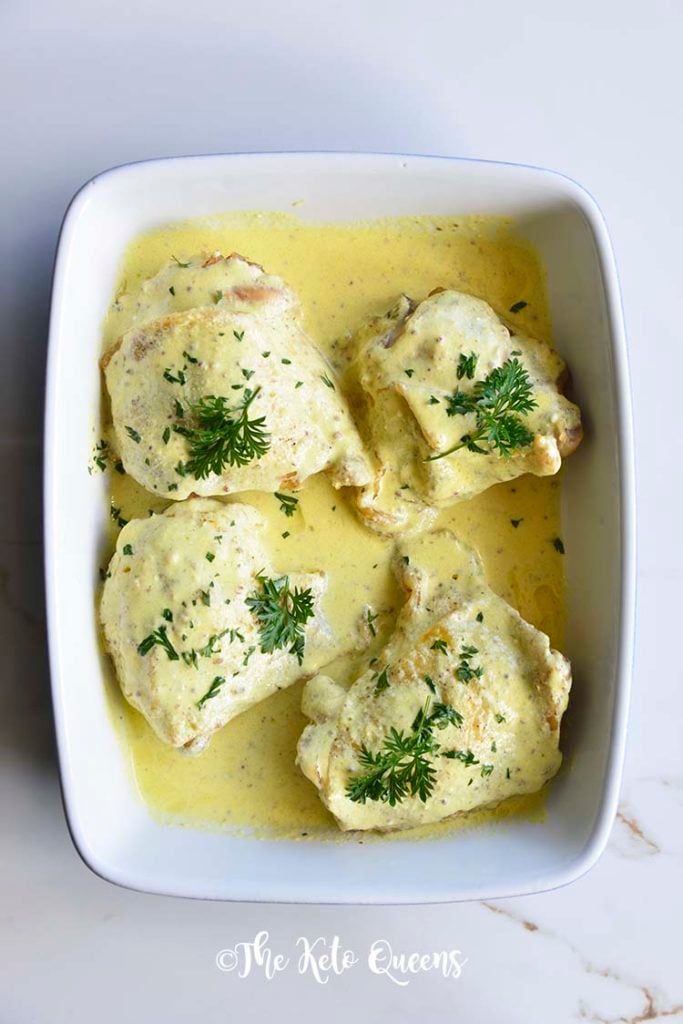 Roasted Chicken Thighs with Creamy Mustard Sauce in a blue and white casserole dish