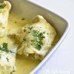 Roasted Chicken Thighs with Creamy Mustard Sauce in a blue and white casserole dish