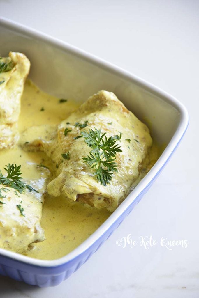 Roasted Chicken Thighs with Creamy Mustard Sauce in a blue and white casserole dish